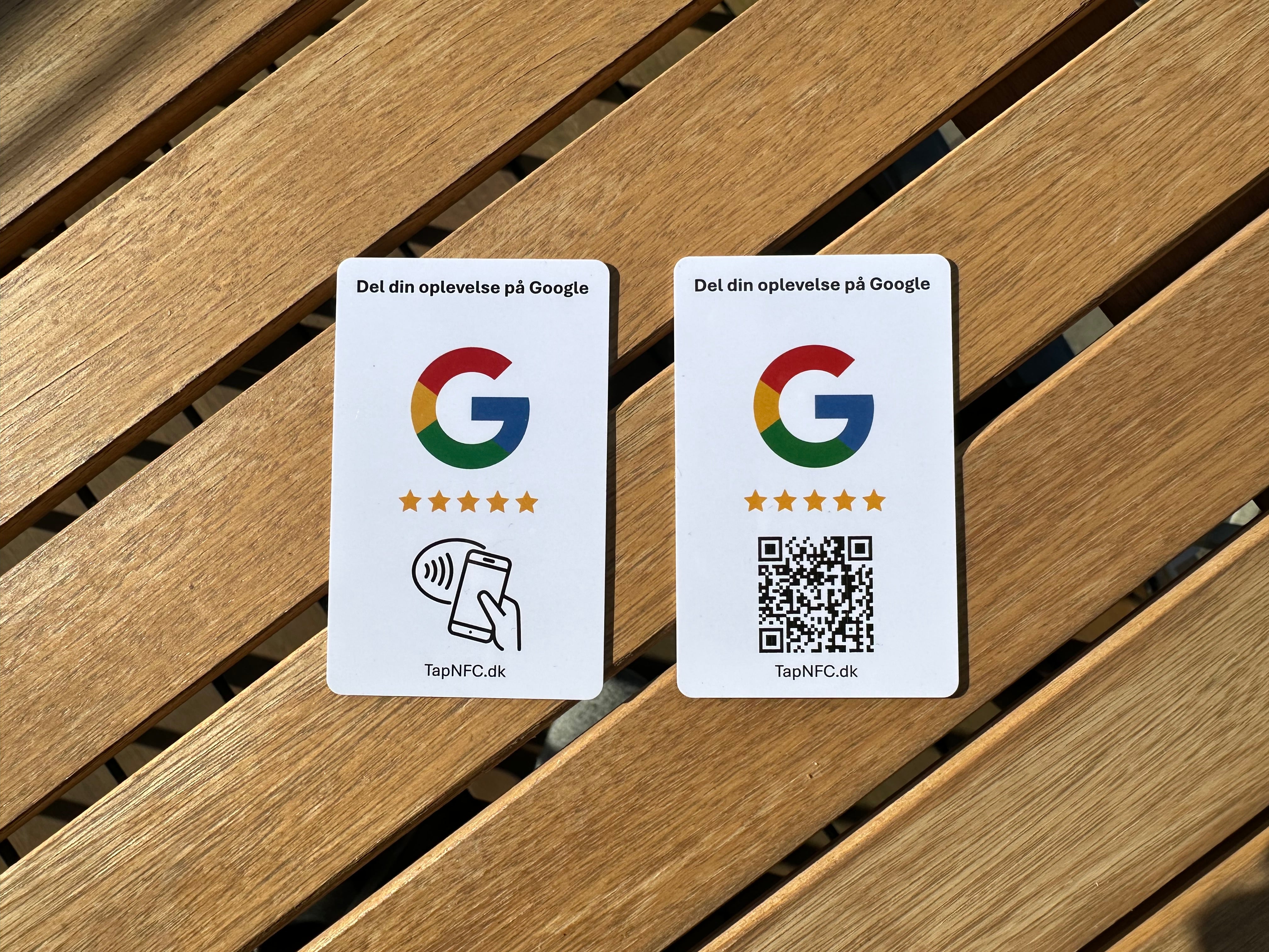 2 anmeldelseskort til googleanmeldelser med NFC og QR kode på et træbord.